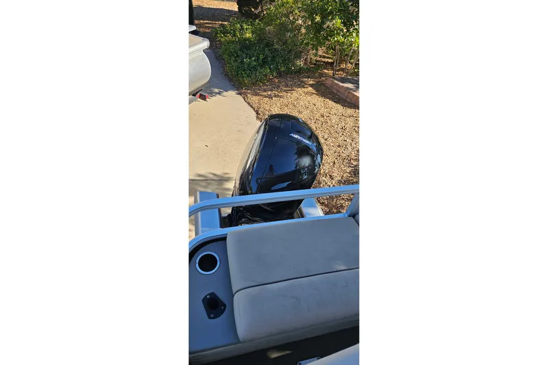 Slide: The Image of 2023 Sun Tracker SportFish 22 XP3 boat with outboard motor, parked on a driveway. - 13