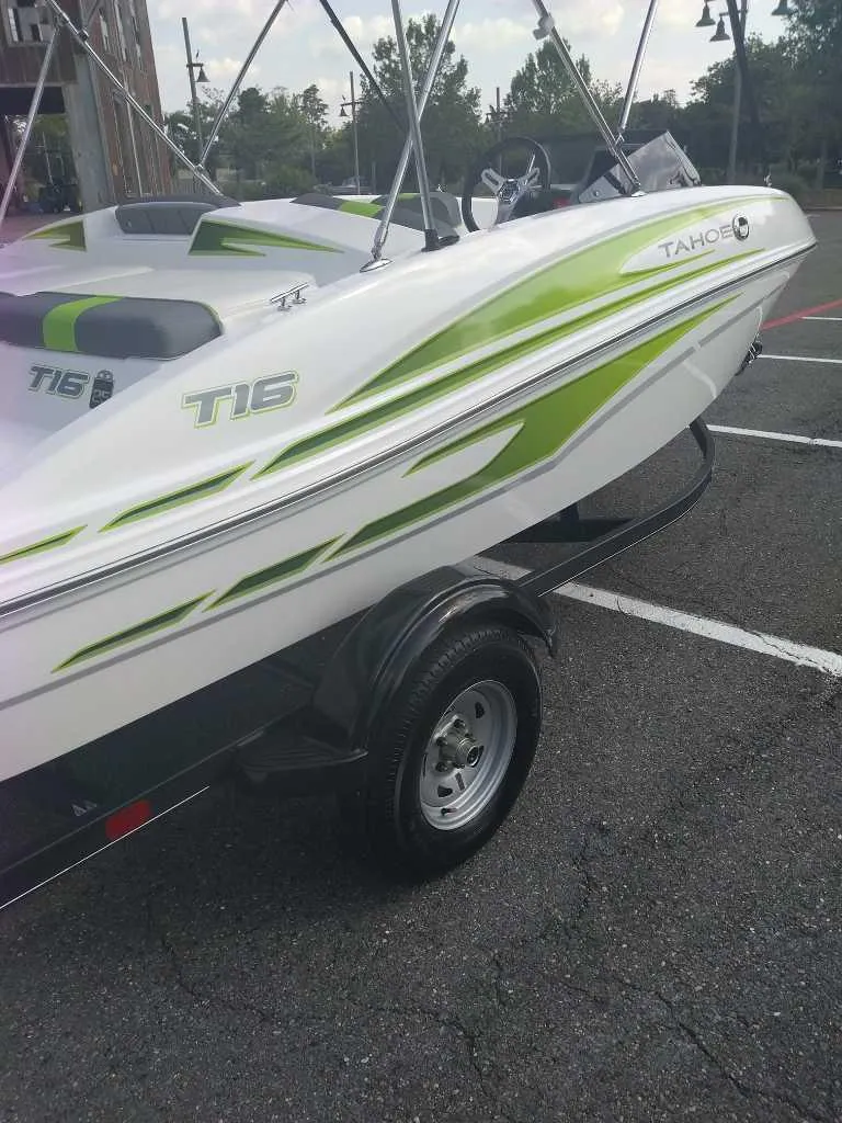 Slide: The Image of 2023 Tahoe T16 boat with green accents on a trailer in a parking lot. - 5