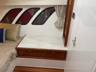 Slide: The Image of 2017 Intrepid 475 Sport Yacht interior cabin with bed, windows, and wooden furniture. - 12
