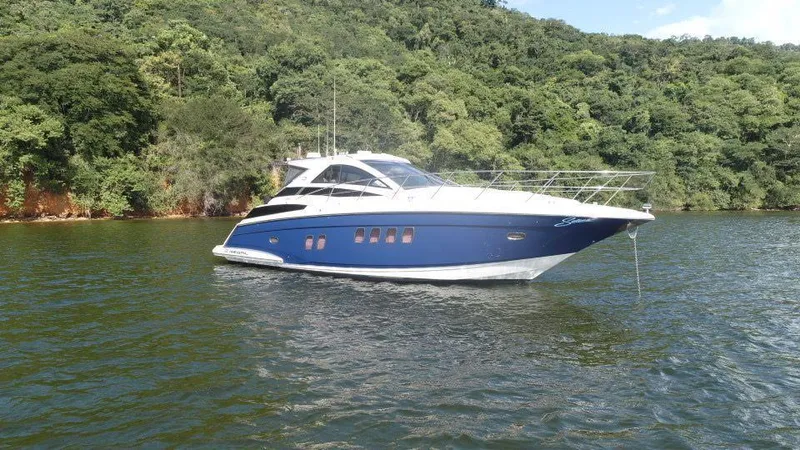 The Image of 2015 Regal 42 Sport Coupe yacht on a serene lake with lush green forest background. - 0