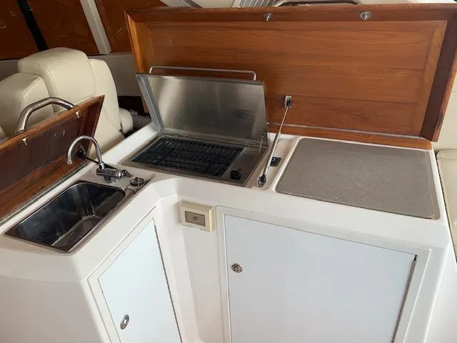Slide: The Image of 2015 Regal 42 Sport Coupe yacht kitchenette with sink, grill, and storage cabinets. - 17