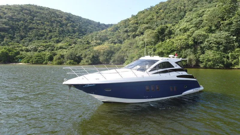 Slide: The Image of 2015 Regal 42 Sport Coupe yacht on a scenic lake with lush green hills. - 2