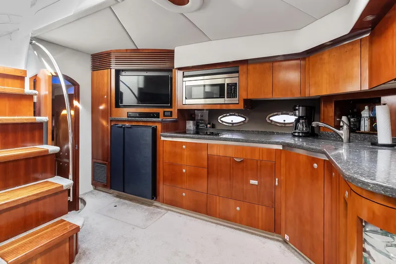 Slide: The Image of 2007 Cruisers Yachts 520 Express kitchen with wooden cabinetry, microwave, and stairs. - 5