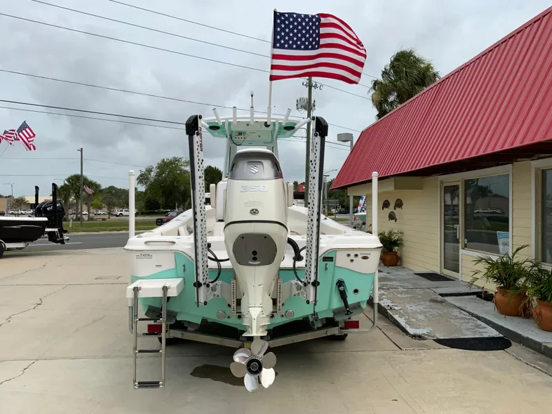Slide: The Image of 2021 Blue Wave 2800 Makaira boat with American flag, docked near a red-roofed building. - 2