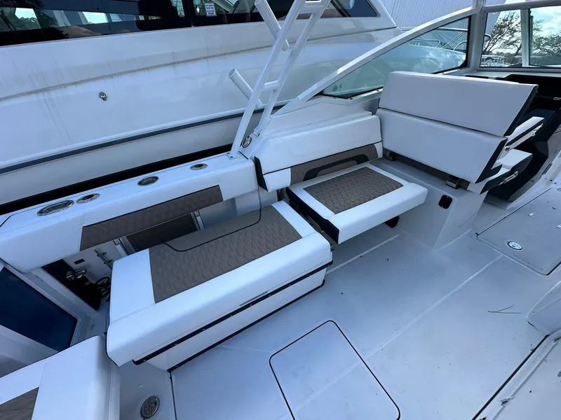 Slide: The Image of 2024 Blackfin 272 DC boat interior seating area with white and brown cushions. - 13