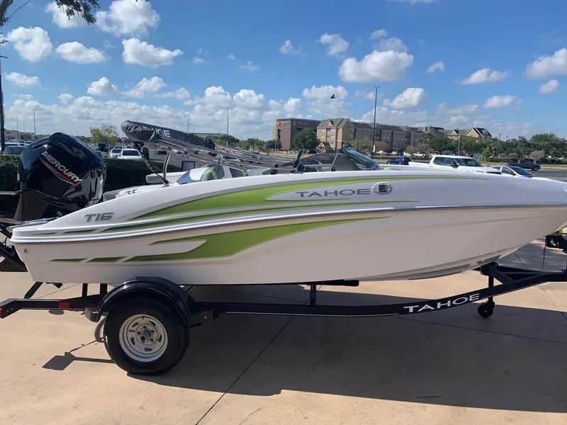 Slide: The Image of 2023 Tahoe T16 boat with green accents on a trailer, parked outdoors. - 0