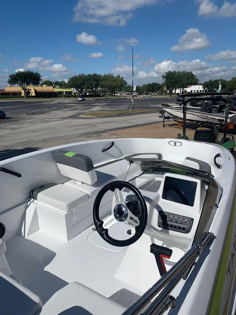 Slide: The Image of 2023 Tahoe T16 boat interior with steering wheel and dashboard, parked outdoors. - 1
