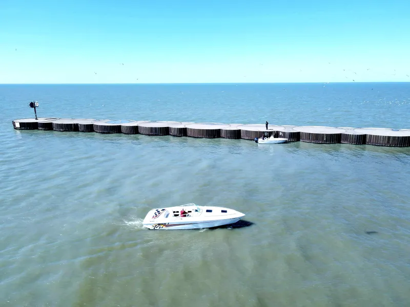 Slide: The Image of 1999 Baha Cruisers 290 Mach 1 boat cruising near a breakwater on a sunny day. - 3