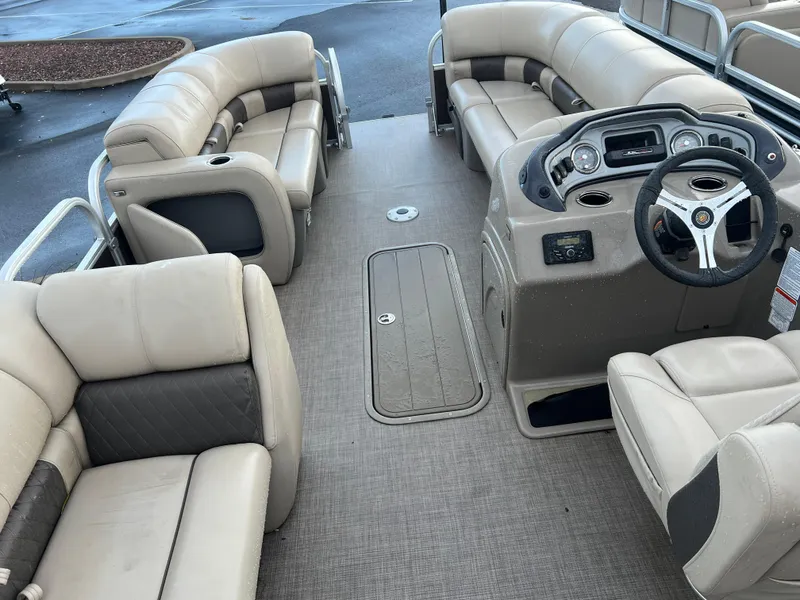 Slide: The Image of 2023 Sun Tracker SportFish 22 XP3 pontoon boat interior with beige seating and steering console. - 2