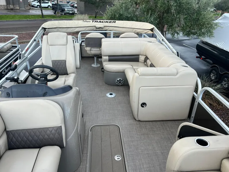 Slide: The Image of 2023 Sun Tracker SportFish 22 XP3 pontoon boat interior with beige seating and steering console. - 3