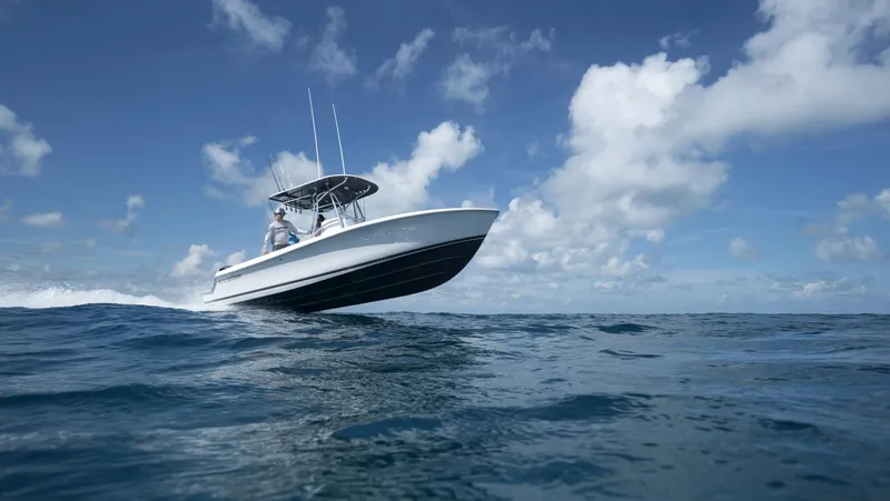 Slide: The Image of 2024 Contender 24S boat cruising on open water under a clear blue sky. - 7