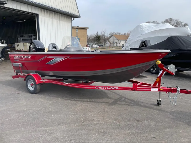 The Image of 2023 Crestliner 1650 Fish Hawk boat on a red trailer outside a warehouse. - 0