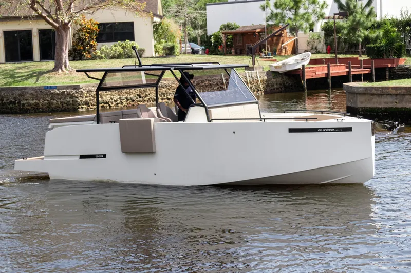 Slide: The Image of 2024 De Antonio Yachts D28 Xplorer cruising on a calm river near residential area. - 2