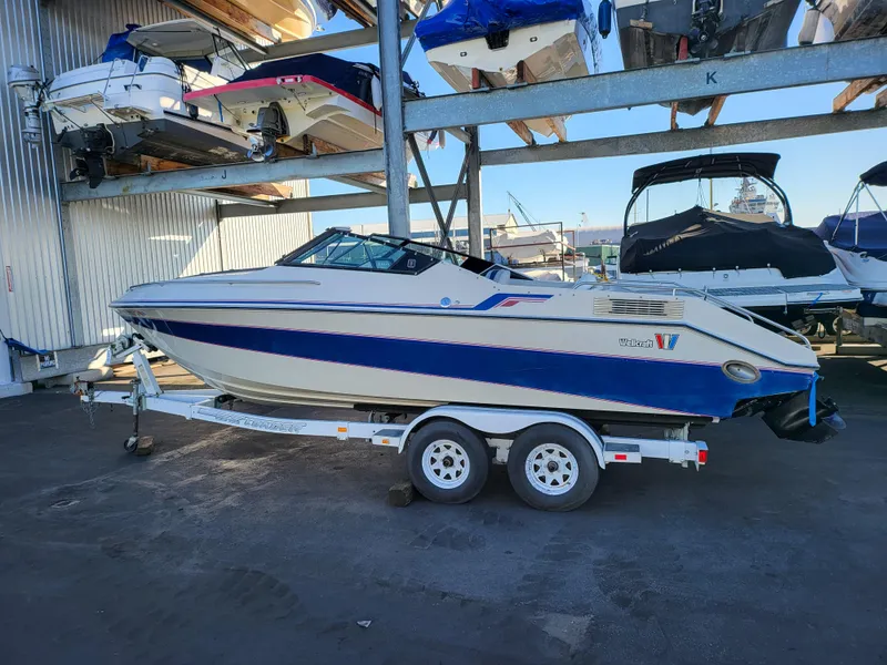 The Image of 1988 Wellcraft 220 Elite boat on a trailer in a marina storage area. - 1