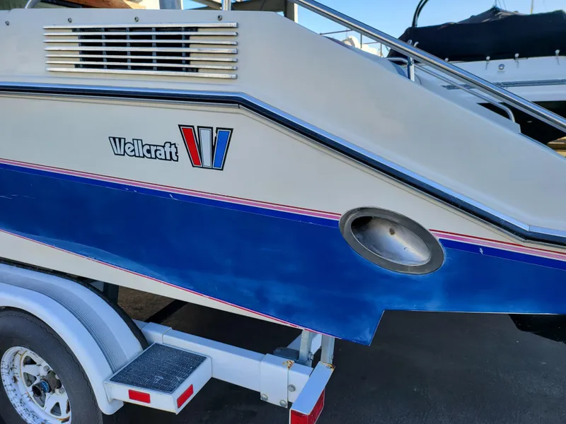 Slide: The Image of 1988 Wellcraft 220 Elite boat on trailer, side view showing logo and blue stripe. - 13