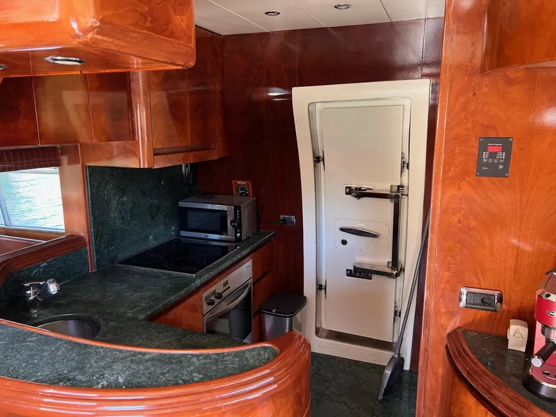 Slide: The Image of Luxurious kitchen in a 2001 Maiora 20 yacht with modern appliances and wooden cabinetry. - 14
