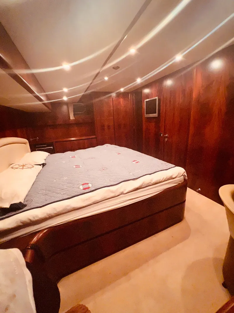 Slide: The Image of Luxurious bedroom interior of 2001 Maiora 20 yacht with wood paneling and cozy lighting. - 20