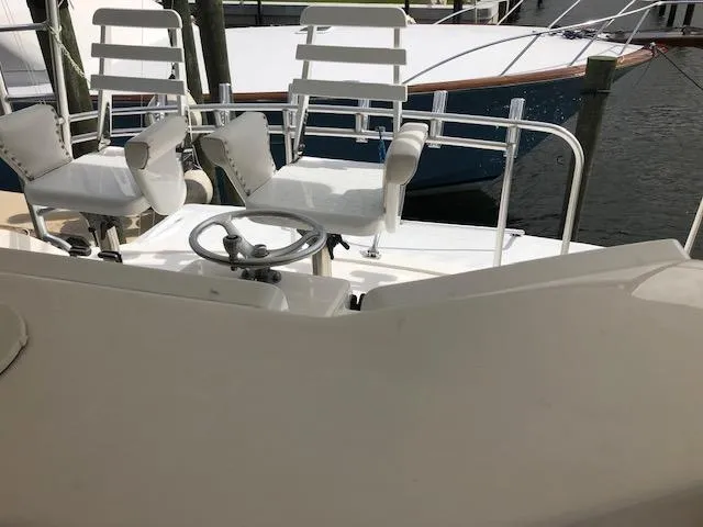 Slide: The Image of 2000 Bertram 510 Convertible boat helm with white captain chairs at dock. - 3