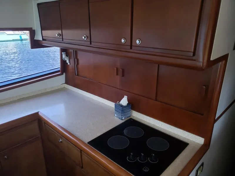 Slide: The Image of 2000 Bertram 510 Convertible yacht kitchen with electric stove and wooden cabinets. - 5