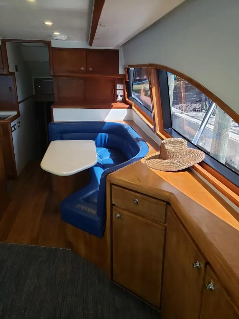 Slide: The Image of Interior of a 2000 Bertram 510 Convertible yacht with blue seating and wooden cabinetry. - 6