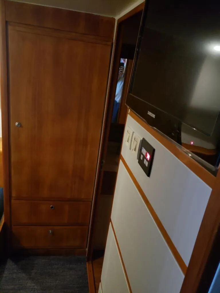 Slide: The Image of Interior of a 2000 Bertram 510 Convertible yacht with wooden cabinetry and mounted TV. - 8