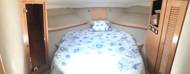 Slide: The Image of 1997 Bertram Convertible boat cabin with a cozy bed and wooden storage cabinets. - 11