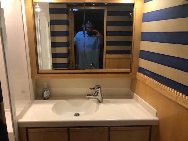 Slide: The Image of 1997 Bertram Convertible bathroom with sink, mirror, and striped wallpaper. - 14