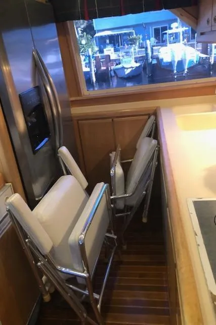 Slide: The Image of Interior of a 1997 Bertram Convertible yacht with folded chairs and a stainless steel refrigerator. - 44