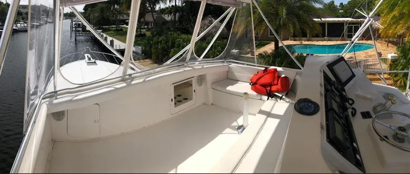 Slide: The Image of 1997 Bertram Convertible yacht deck with navigation controls and life jackets, docked near a pool. - 5
