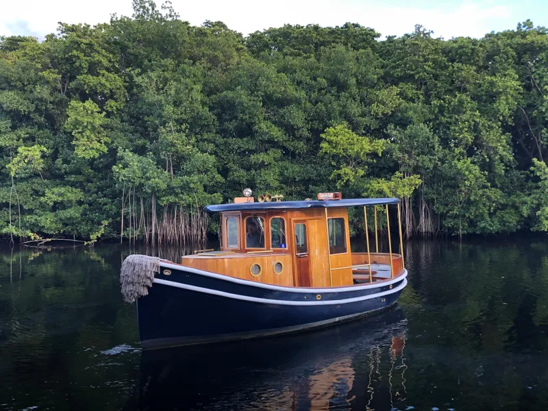 Slide: The Image of Vintage 1992 Crosby Tug boat on calm water with lush green forest backdrop. - 0