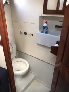 Slide: The Image of 1992 Crosby Tug boat bathroom with toilet, sink, and cleaning supplies. - 14