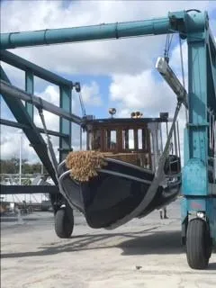 Slide: The Image of Crosby Tug 1992 being lifted by a boat hoist at a marina. - 16