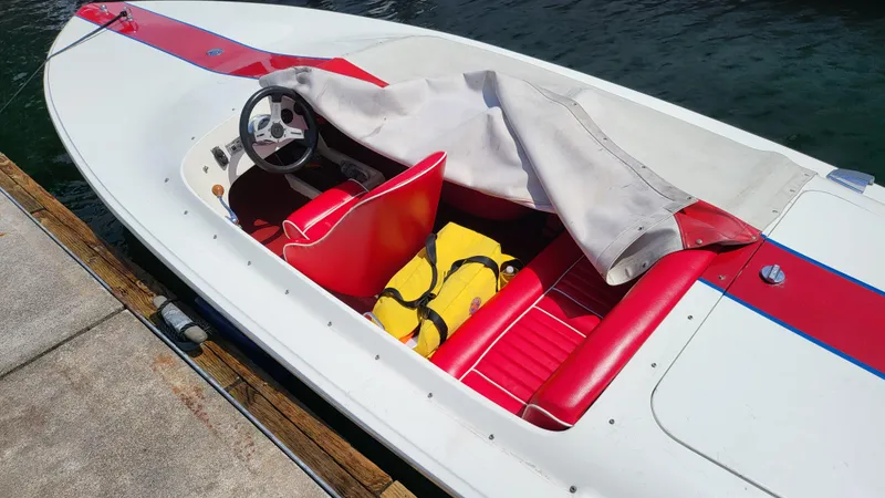 Slide: The Image of 1973 Donzi X18 speedboat with red and white interior docked by the water. - 2
