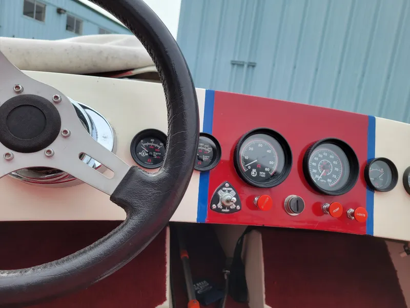 Slide: The Image of 1973 Donzi X18 dashboard with steering wheel and gauges, featuring a red and blue panel design. - 7