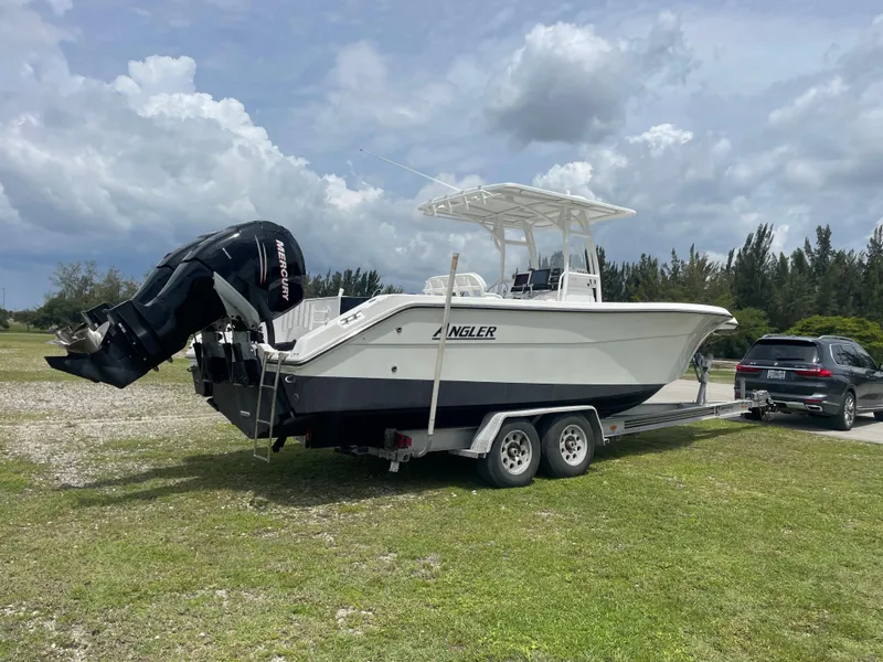 Slide: The Image of 2006 Angler 2900CC boat on a trailer with a car in a grassy area. - 12