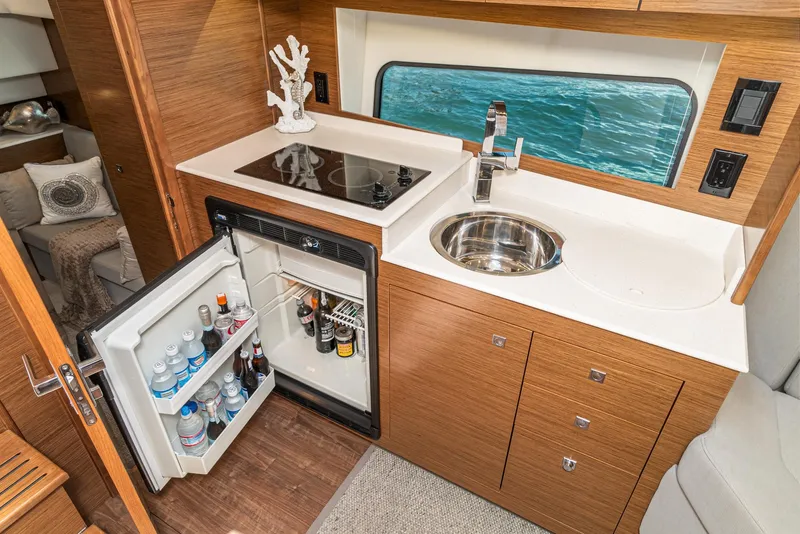 Slide: The Image of 2017 Cruisers Yachts 390 Express Coupe kitchen with open fridge, sink, and stove. - 30