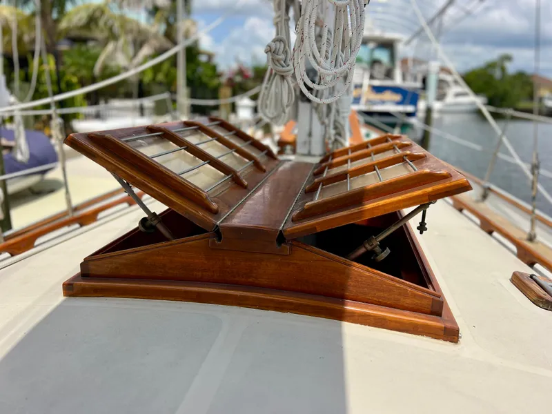 Slide: The Image of 1986 Cherubini 44 sailboat with open wooden deck hatches in a marina. - 19