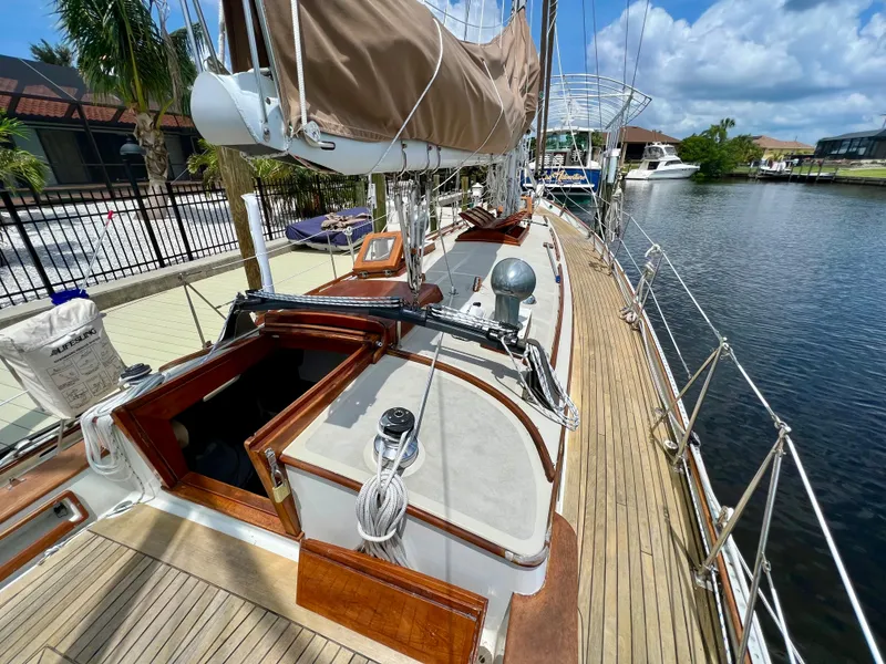 Slide: The Image of 1986 Cherubini 44 sailboat docked by a canal, showcasing its deck and rigging. - 20