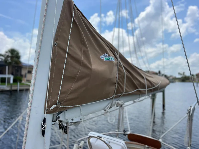Slide: The Image of 1986 Cherubini 44 sailboat with brown sail cover docked by the water. - 26