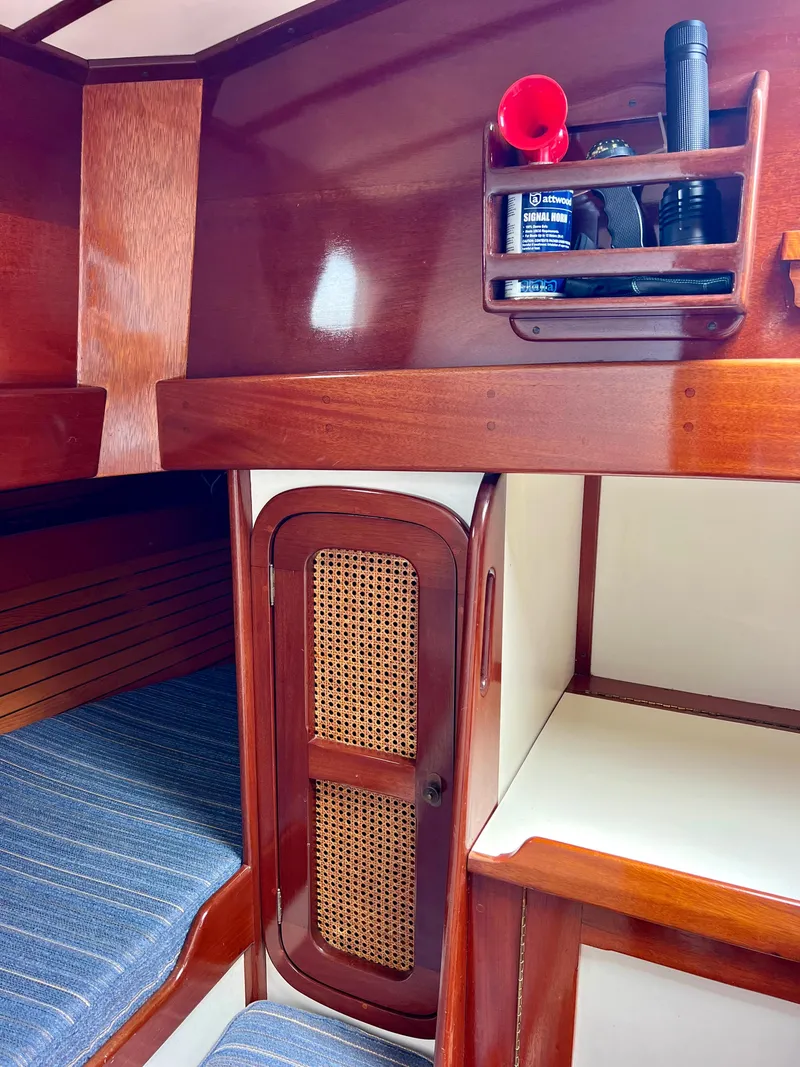 Slide: The Image of Interior cabin of a 1986 Cherubini 44 sailboat with wooden finishes and storage shelves. - 37