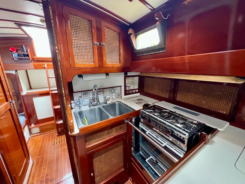 Slide: The Image of Cherubini 44 1986 yacht kitchen with wood cabinetry, double sink, and stove. - 46