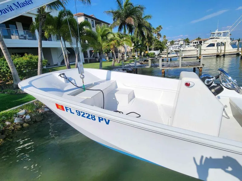 Slide: The Image of 1976 Boston Whaler 17 Montauk boat docked near waterfront homes and palm trees. - 14