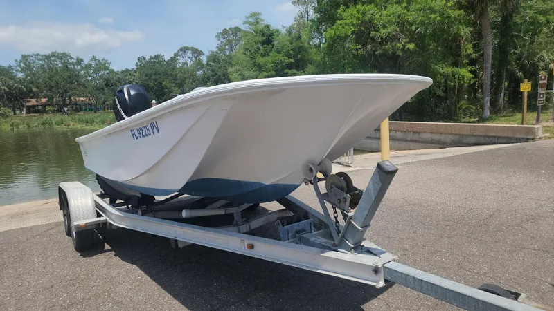 Slide: The Image of 1976 Boston Whaler 17 Montauk boat on trailer, parked near a lake with trees. - 20