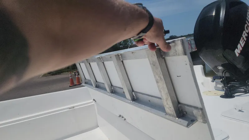 Slide: The Image of Person adjusting ladder on 1976 Boston Whaler 17 Montauk boat with Mercury engine. - 36