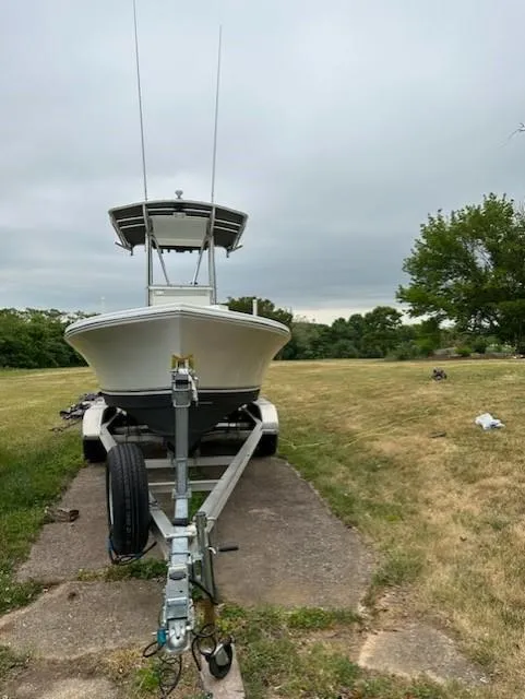 Slide: The Image of 2012 Onslow Bay 20 boat on trailer, parked on grassy area under cloudy sky. - 2