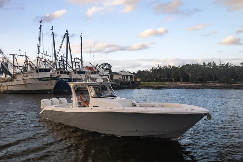 Slide: The Image of 2024 Edgewater 370CC boat cruising near docked ships. - 11