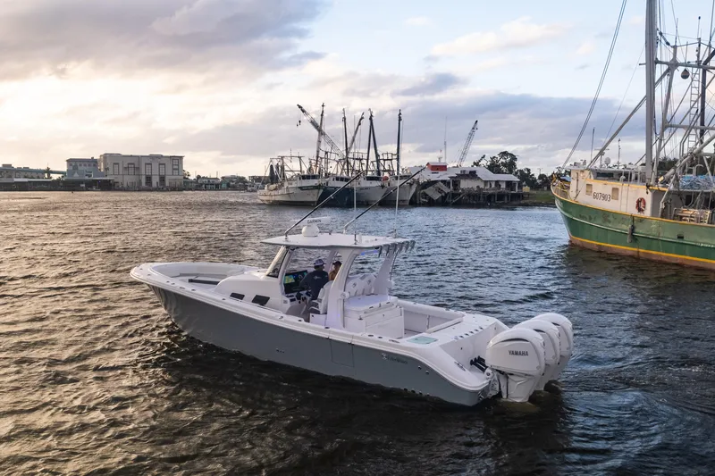 Slide: The Image of 2024 Edgewater 370CC boat cruising near a harbor at sunset. - 21