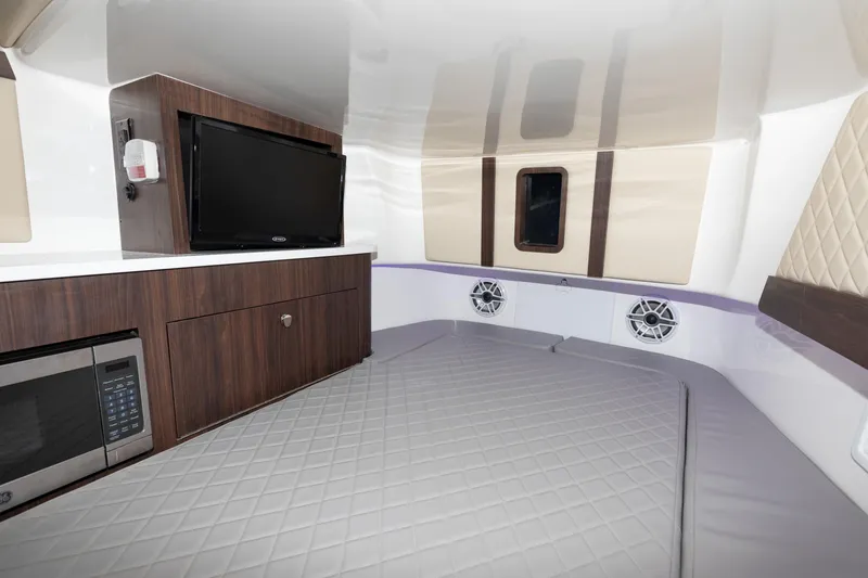 Slide: The Image of 2024 Edgewater 370CC cabin interior with bed, TV, microwave, and storage cabinets. - 27