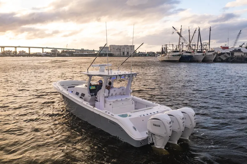 Slide: The Image of 2024 Edgewater 370CC boat cruising in a harbor at sunset. - 33