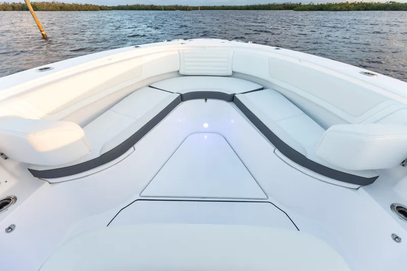 Slide: The Image of 2024 Edgewater 370CC boat bow seating area with white cushions on the water. - 5